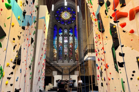 Pessoas em pÃ© atrÃ¡s de cordas para uma parede de escalada na igreja Saint-Antoine reaproveitada em Bruxelas, BÃ©lgica, quarta-feira, 21 de junho de 2023.