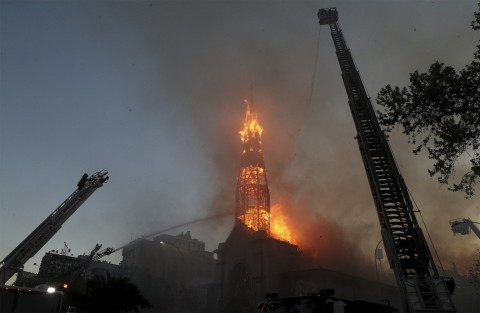 Bombeiros tentam conter o fogo na Igreja La Asunción, incendiada por vândalos encapuzados durante protesto em Santiago, no Chile %u2014 Foto: Esteban Felix/AP